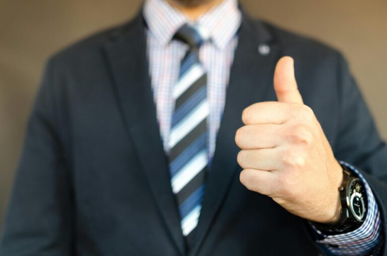A professional man in a suit giving a thumbs-up gesture representing confidence, motivation, success, and positive affirmations.